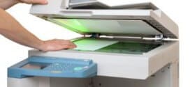 Kopiergerät im Einsatz: Hände legen ein Blatt Papier ins Gerät