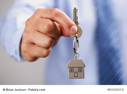 Holding out house keys on a house shaped keychain