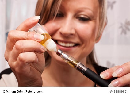 junge blonde Frau befüllt mit Liquid ihre elektrische Zigarette